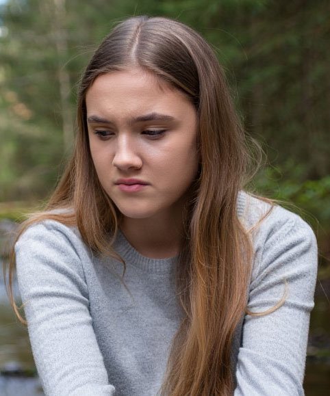 Девушка сидит в лесу одна